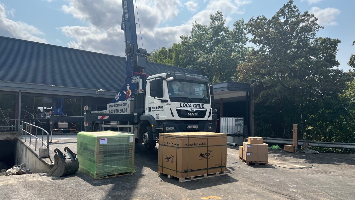 Camion de grue préparant l'installation de panneaux solaires.