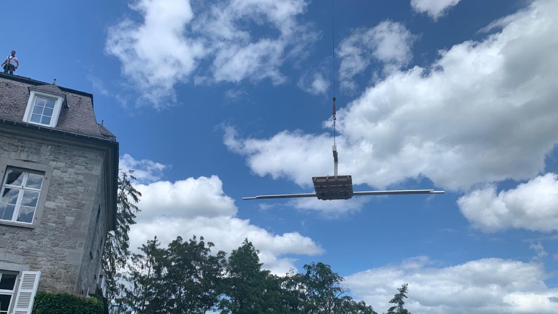 Levage de panneaux solaires par grue sur un manoir.