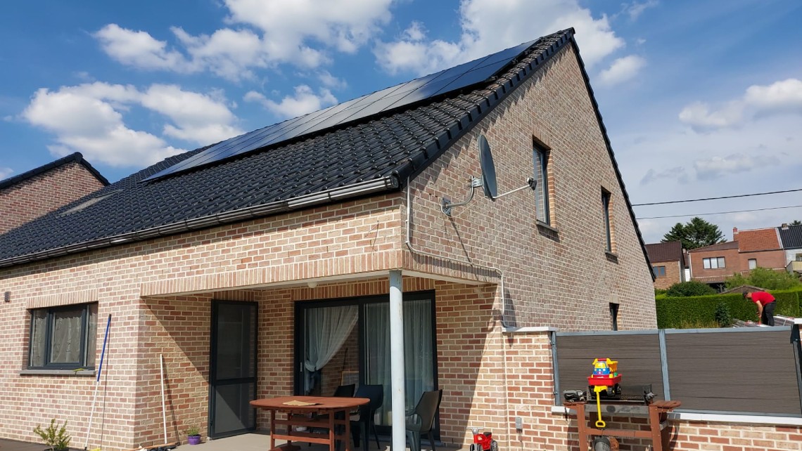 Maison en briques avec installation de panneaux solaires sur le toit.