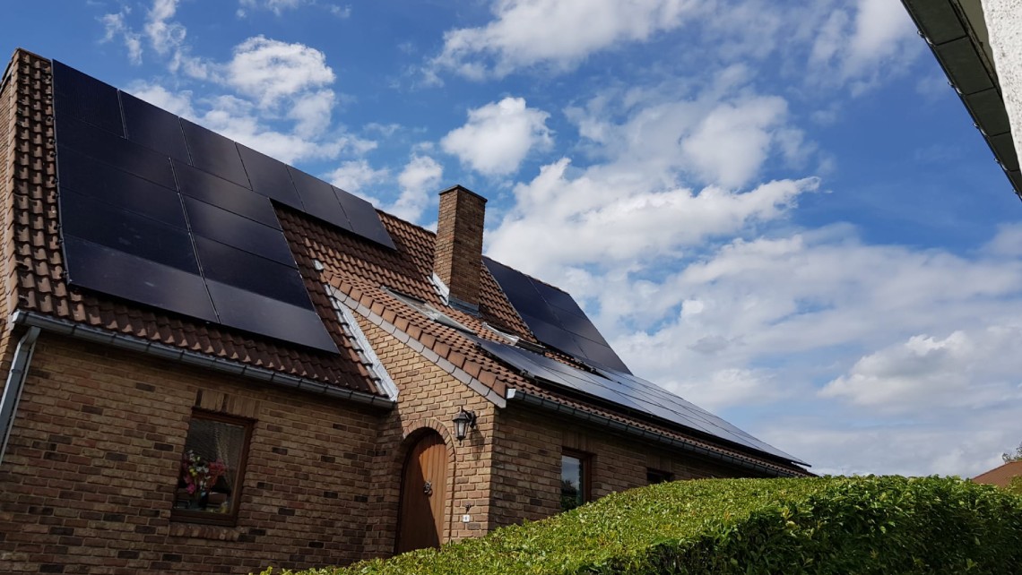 Maison avec un toit en tuiles et des panneaux solaires noirs.