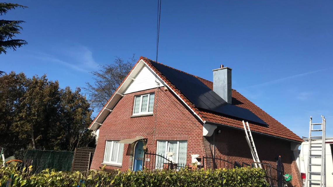 Maison avec toit en tuiles et panneaux solaires intégrés.