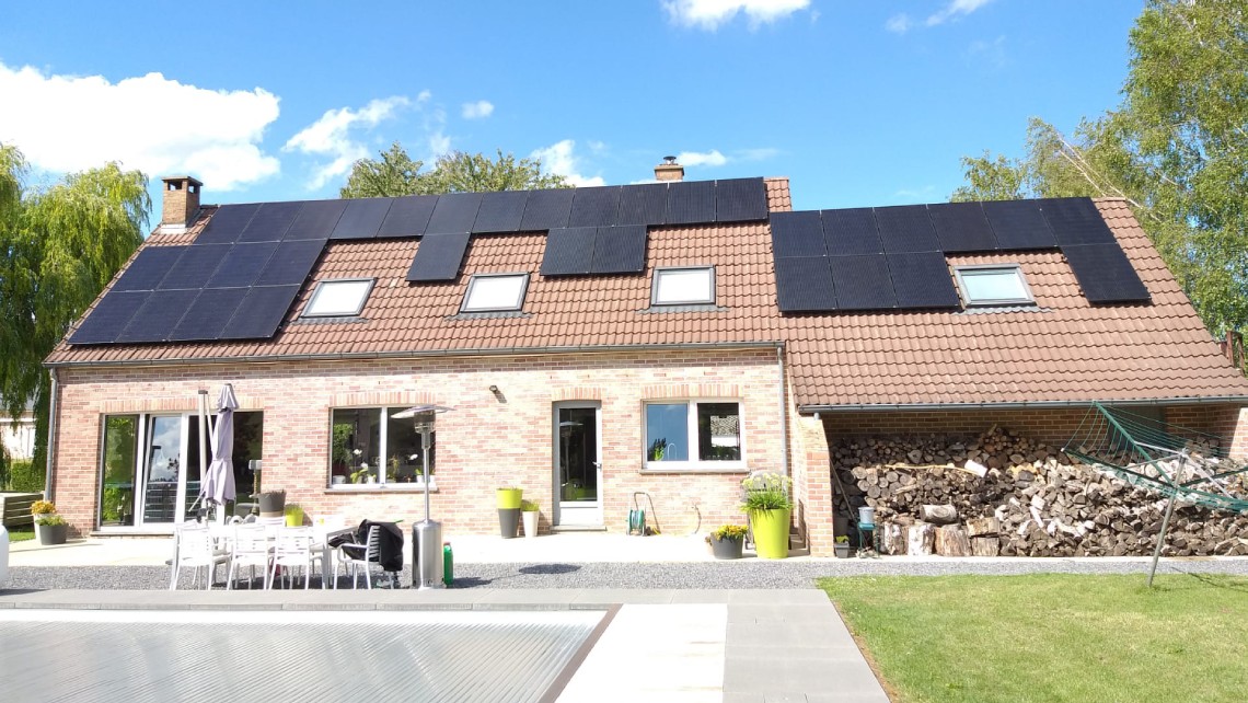 Terrasse arrière d'une maison avec des panneaux solaires sur le toit.